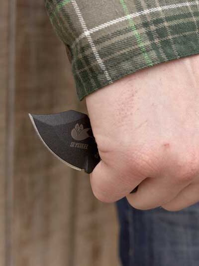 A photograph of a single edge Final Option Blade deployed in reverse grip with fist down.